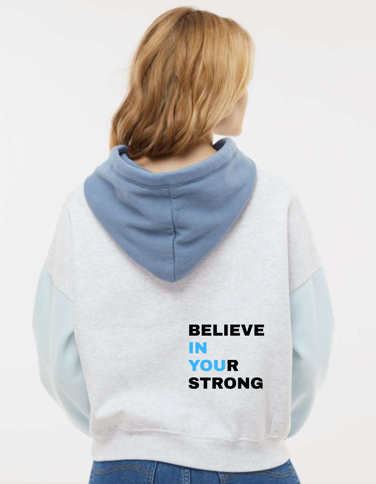 Person wearing a light blue and white hoodie with 'BELIEVE IN YOUR STRONG' text on the back.